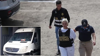 Nadeska Widausky, rubia, vestida de blanco con chaleco de "Interpol Detenido", esposada, escoltada por dos agentes en un camino de tierra, junto a una ambulancia blanca