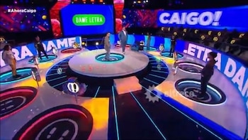 Varias personas sobre plataformas circulares en la escenografía iluminada de un estudio de televisión con pantallas