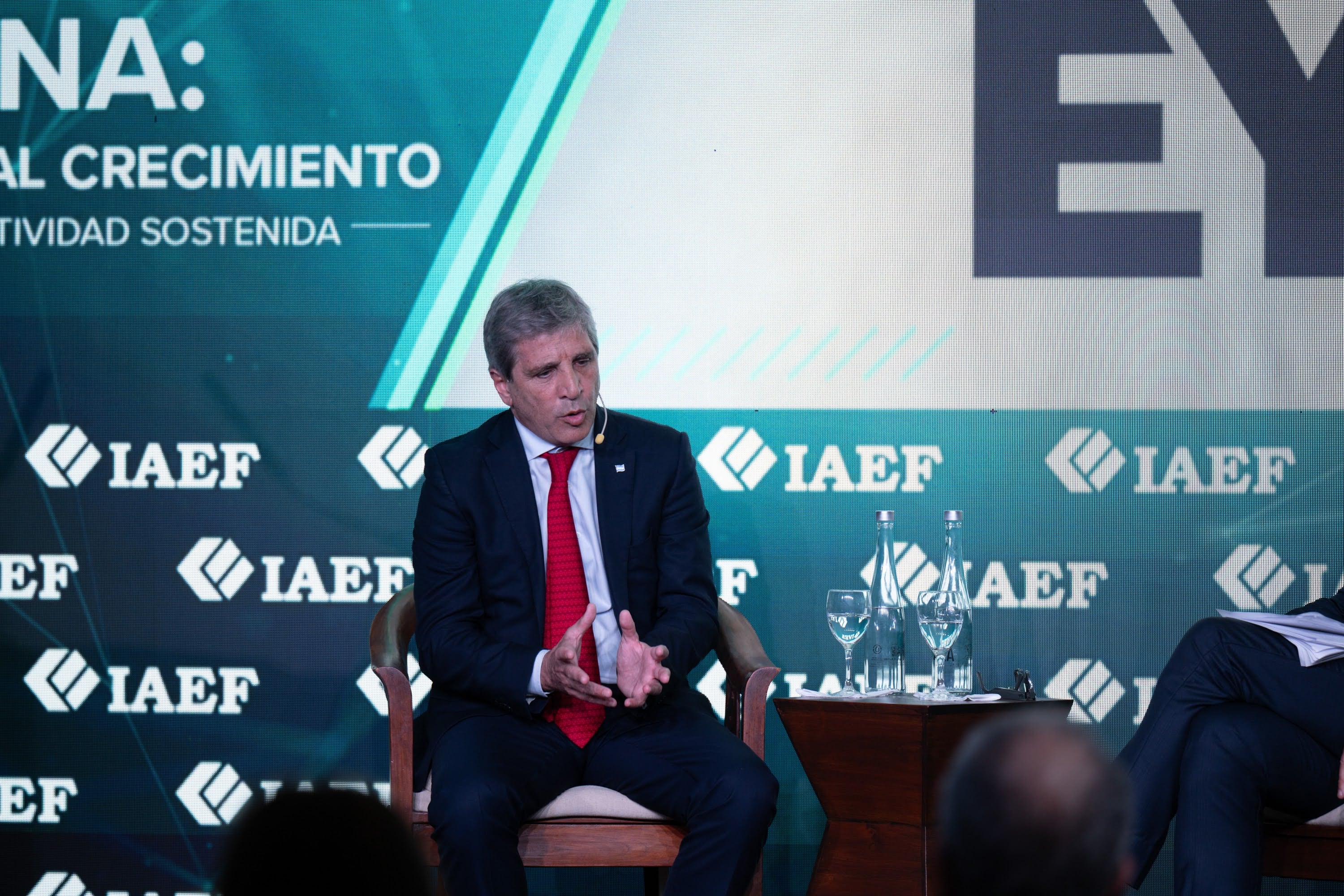 Luis Caputo habla durante la Convención Anual del Instituto Argentino de Ejecutivos de Finanzas sobre un escenario con pantallas institucionales.