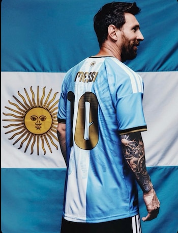 Lionel Messi de espaldas con la camiseta albiceleste y el número 10 frente a la bandera de Argentina