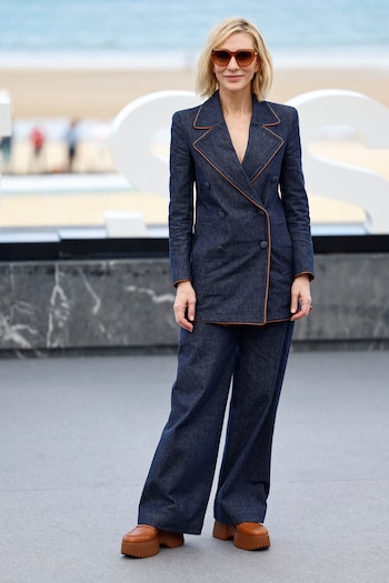 Traje azul oscuro con ribetes marrón claro y accesorios que refuerzan el estilo sofisticado al aire libre