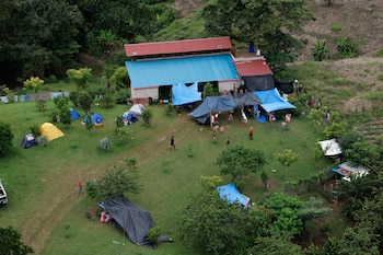 Vista desde arriba de una casa rodeada por tiendas de campaña de colores y lonas sobre un terreno llano cubierto de césped