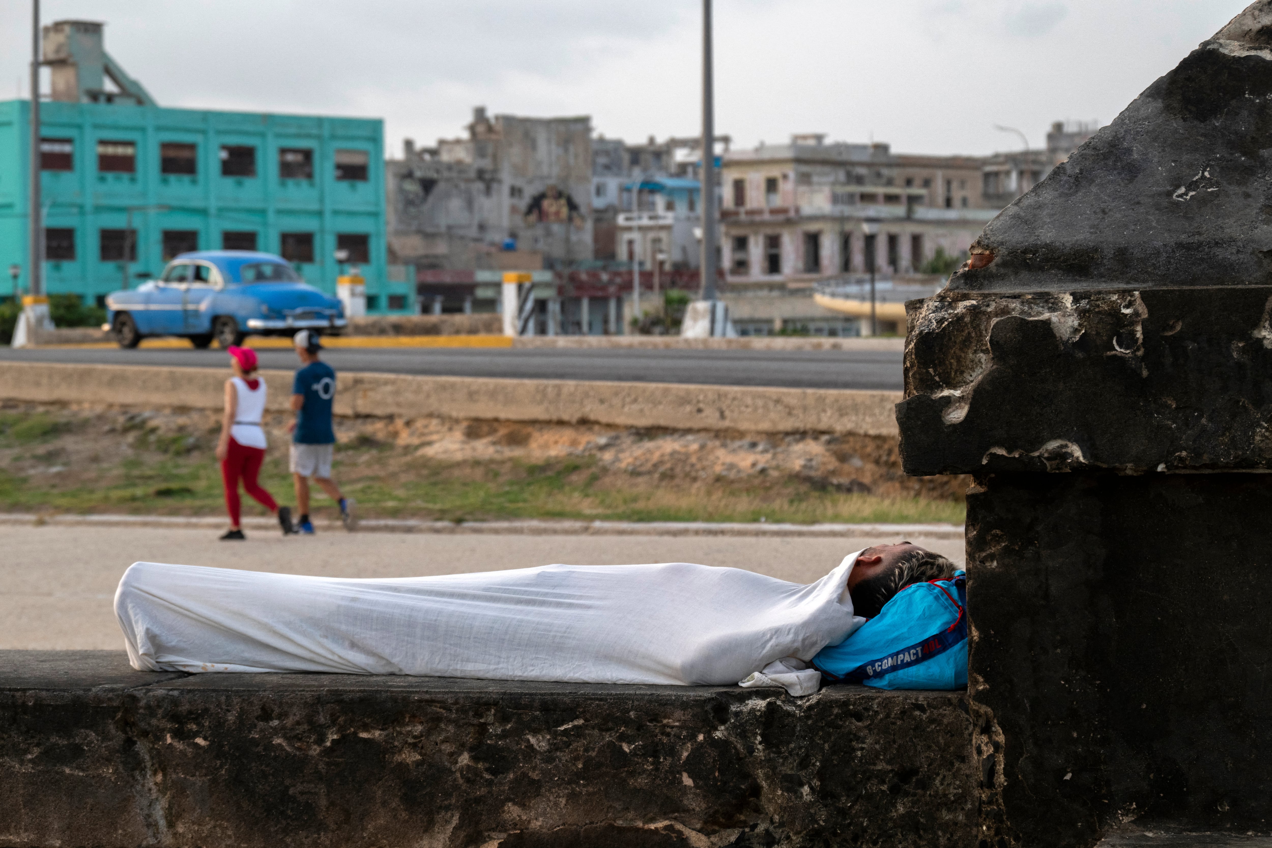 Un hombre duerme en el malecón de La Habana en busca de alivio ante las altas temperaturas y los frecuentes apagones. 13 de agosto de 2026. (Yamil Lage / AFP)