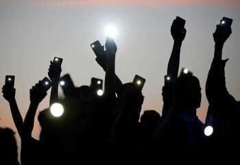 Manifestantes sostienen sus teléfonos con