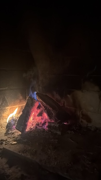 Troncos de madera sobre brasas rojas y llamas de fuego dentro de una chimenea de ladrillos
