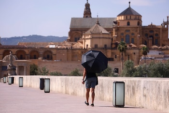 Una persona usa un paraguas para protegerse del sol mientras pasea por el Puente Romano de Córdoba. (EFE/Salas)