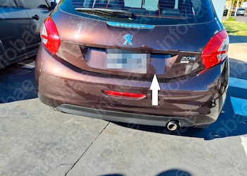 Parte trasera de un coche Peugeot 208 marrón con matrícula borrosa, luces traseras rojas, un tubo de escape y una flecha blanca