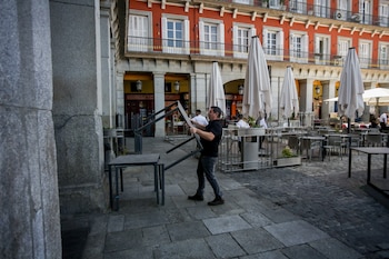 Un camarero recoge la terraza del restaurante en el que trabaja.