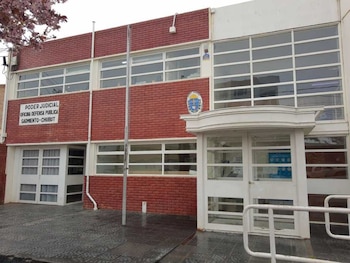 Edificio de ladrillo con ventanas de marco blanco y un cartel con el texto Poder Judicial Oficina Defensa Pública Sarmiento Chubut