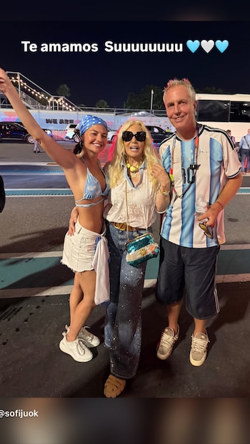 Tres personas posan de noche: una mujer rubia con gafas, una mujer más joven con pañuelo azul y un hombre con camiseta de fútbol argentina