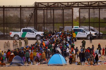 Migrantes esperan cerca del muro