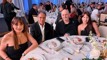Cuatro personas, Viviana Zocco, Daniel Hadad, Juan José Campanella y Cecilia Monti, sentadas en una mesa formal con manteles blancos y vajilla en una cena