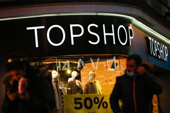 Pedestrians pass a Topshop store