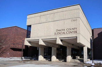 Fachada de hormigón con la inscripción Dakota County Judicial Center y el número 1560 bajo un cielo azul