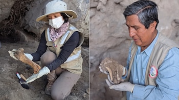 Una mujer con sombrero, mascarilla y guantes manipula un hueso. Un hombre con guantes sostiene un objeto de piedra. Ambos están en un sitio rocoso con tierra