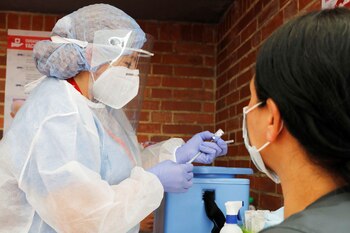 Fotografía de archivo en la que se registró a una enfermera al preparar una dosis de una vacuna contra la covid-19, antes de aplicársela a una mujer, en Bogotá (Colombia). EFE/Carlos Ortega