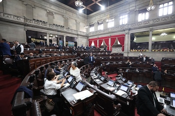 Vista general de una gran cámara legislativa con muchos legisladores sentados en escaños de madera, con pantallas individuales, bajo un techo alto y ornamentado