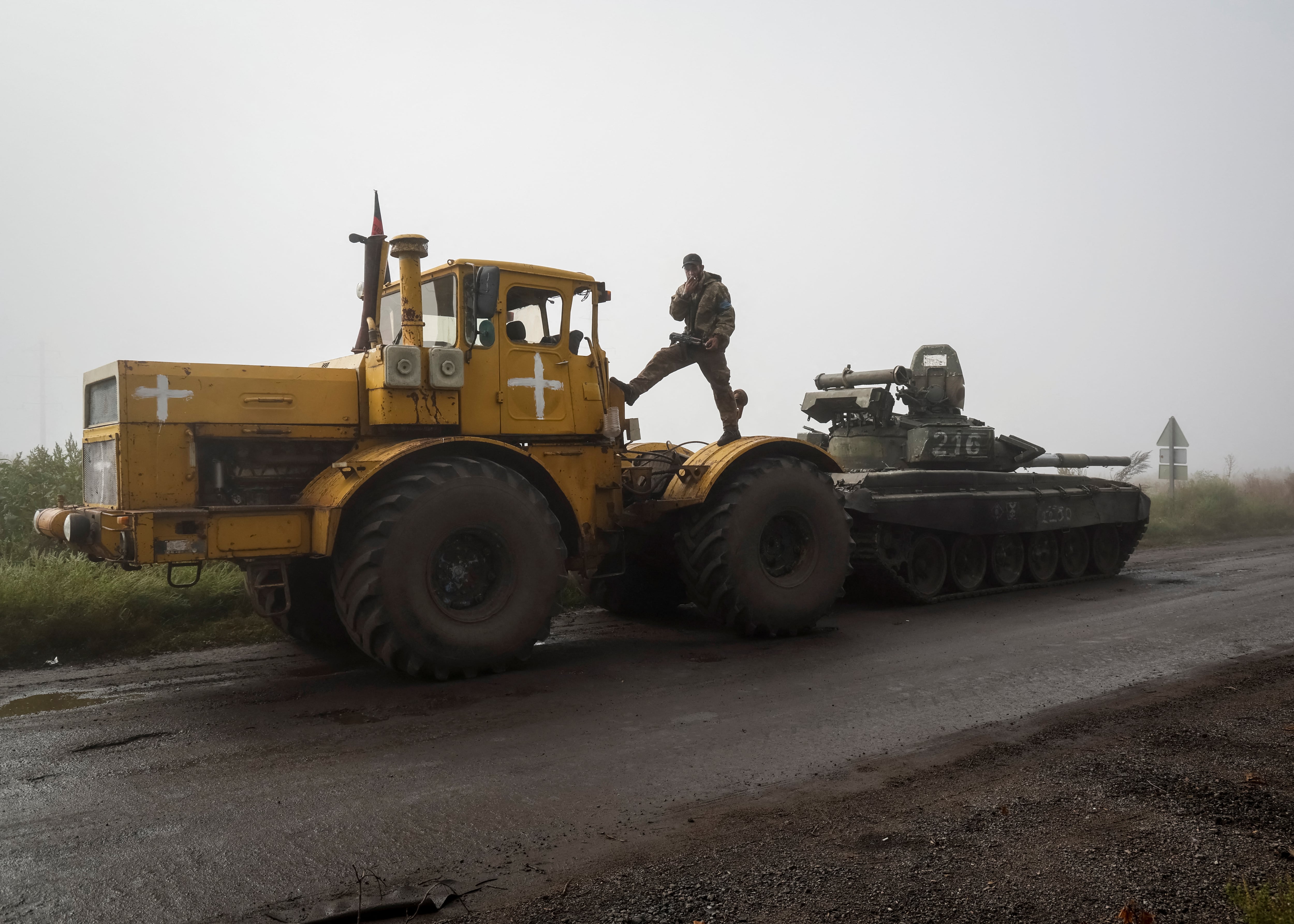Un soldado ucraniano descansa y fuma sobre un tractor mientras remolca un tanque ruso capturado cerca de Izium, en la región de Kharkiv, en septiembre de 2022. La imagen del tractor arrastrando blindados rusos se convirtió en un meme viral y en símbolo del fracaso del plan inicial del Kremlin (REUTERS/Gleb Garanich)