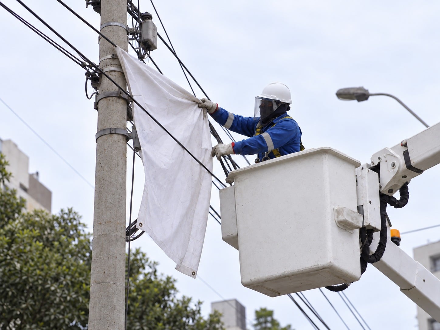 Un operario retira una banderola colgada en un poste de energía tras la advertencia de Luz del Sur sobre los peligros de la propaganda electoral en la red eléctrica. (Foto: Luz del Sur)
