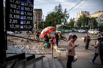 FILE — A currency exchange board and a street vendor at an intersection in Bishkek, Kyrgyzstan, April 28, 2026. A Moscow firm uses shell companies and cryptocurrency to launder money, and a custom app to forge trade records, to help Russia bypass sweeping financial restrictions. (Sergey Ponomarev/The New York Times)