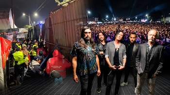 Cinco músicos posan al frente mientras al fondo se observan una multitud en un concierto nocturno y agentes de policía junto a una valla.
