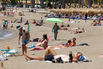 Un hombre vende sombrillas en la playa de la Malagueta, donde la máxima de la temperatura alcanzará los 27 grados en Málaga, a 19 de mayo de 2026. (EFE/Jorge Zapata)