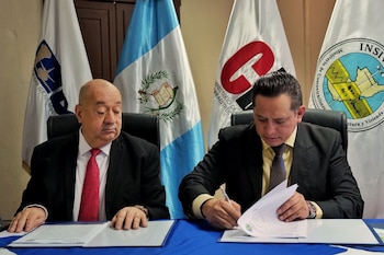 Dos funcionarios en traje firman