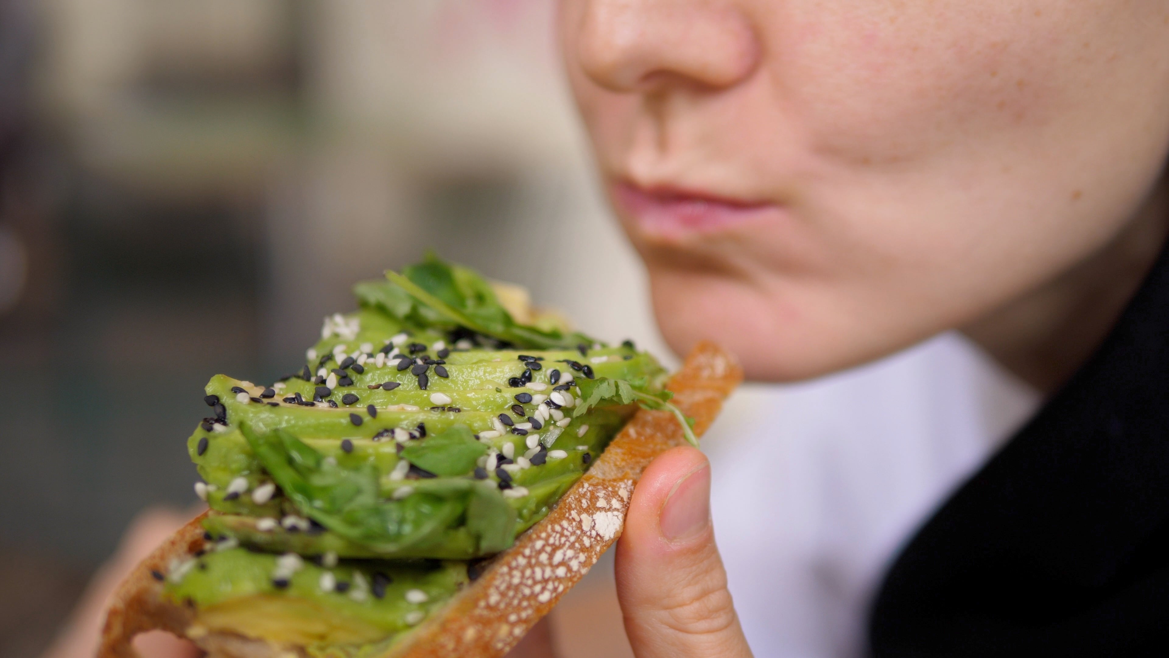 Una mujer comiendo una tostada de aguacate (AdobeStock)