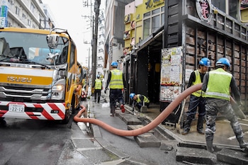 Trabajadores municipales limpian los desagües durante el paso del tifón Saudel en Naha, el 26 de agosto de 2026 (Hiroaki YAMASHIRO/AFP)