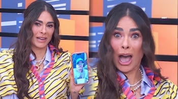 Composición de Galilea Montijo mientras sostiene un teléfono celular en un estudio de televisión y abre la boca frente a la cámara.