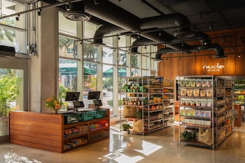 Interior de la tienda Nude Miami. Se ven estantes metálicos llenos de productos, un mostrador de madera con registradoras y grandes ventanales al exterior