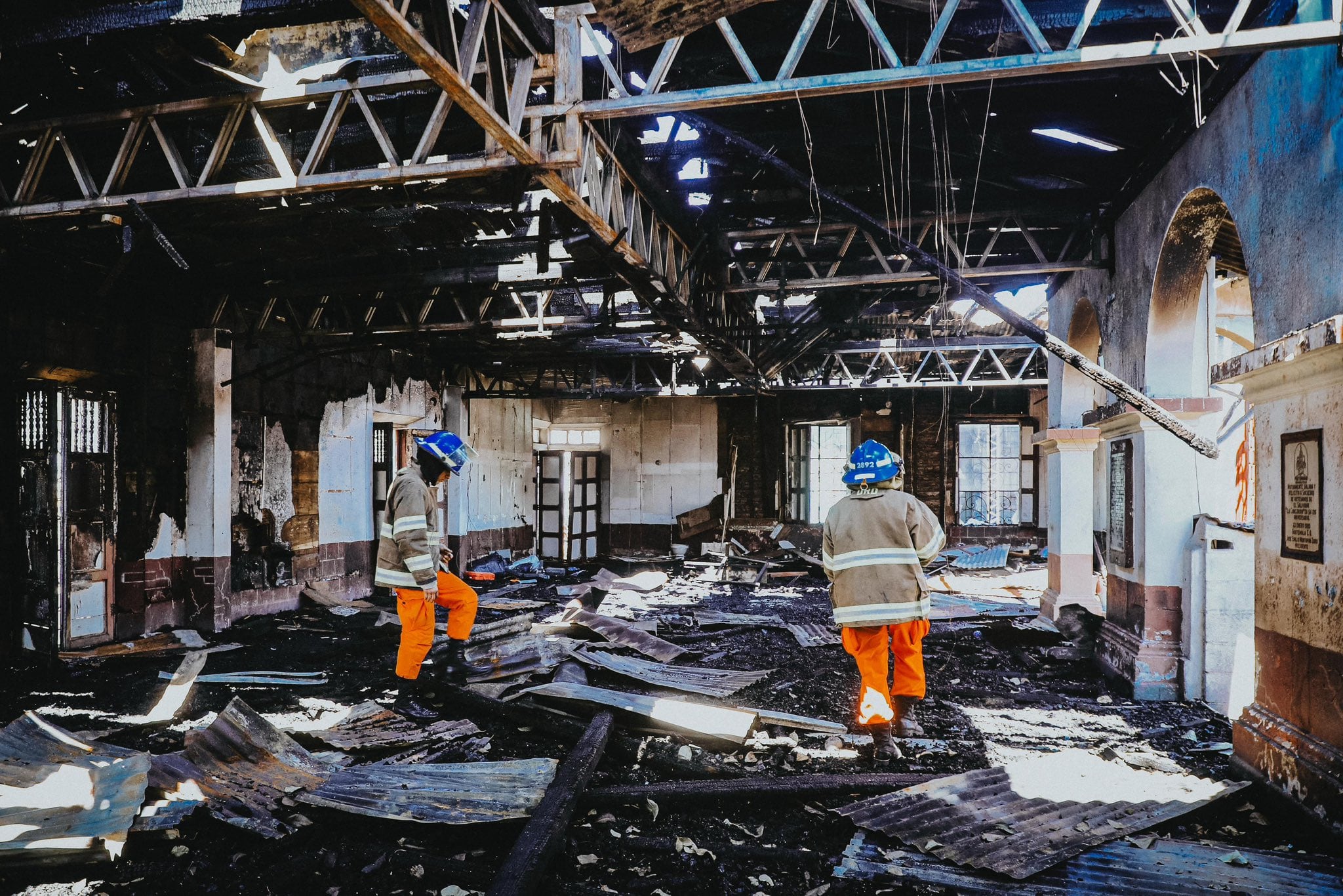 Bomberos inspeccionan el interior de una estructura calcinada tras el incendio en el centro de San Salvador, donde los daños materiales son evidentes y persisten las labores de evaluación y remoción de escombros (Foto cortesía Secretaría de Prensa).