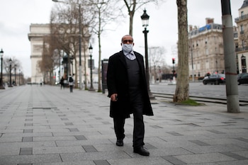 Un hombre camina por Champs Elysees, cerca del Arco de Triunfo, en una París casi desierta
