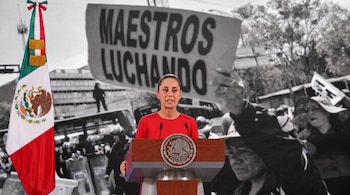 Una mujer en un podio con la bandera de México. El fondo difuminado en blanco y negro muestra personas, policías y un cartel con "MAESTROS LUCHANDO".