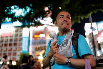 Un hombre usa un ventilador portátil en el distrito comercial y de ocio de Shibuya, Tokio, Japón. REUTERS/Willy Kurniawan