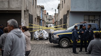 Patrulla policial, cinta amarilla de "PRECAUCION PROHIBIDO EL PASO", tres personas con trajes blancos forenses y agentes en una calle de Tecámac.