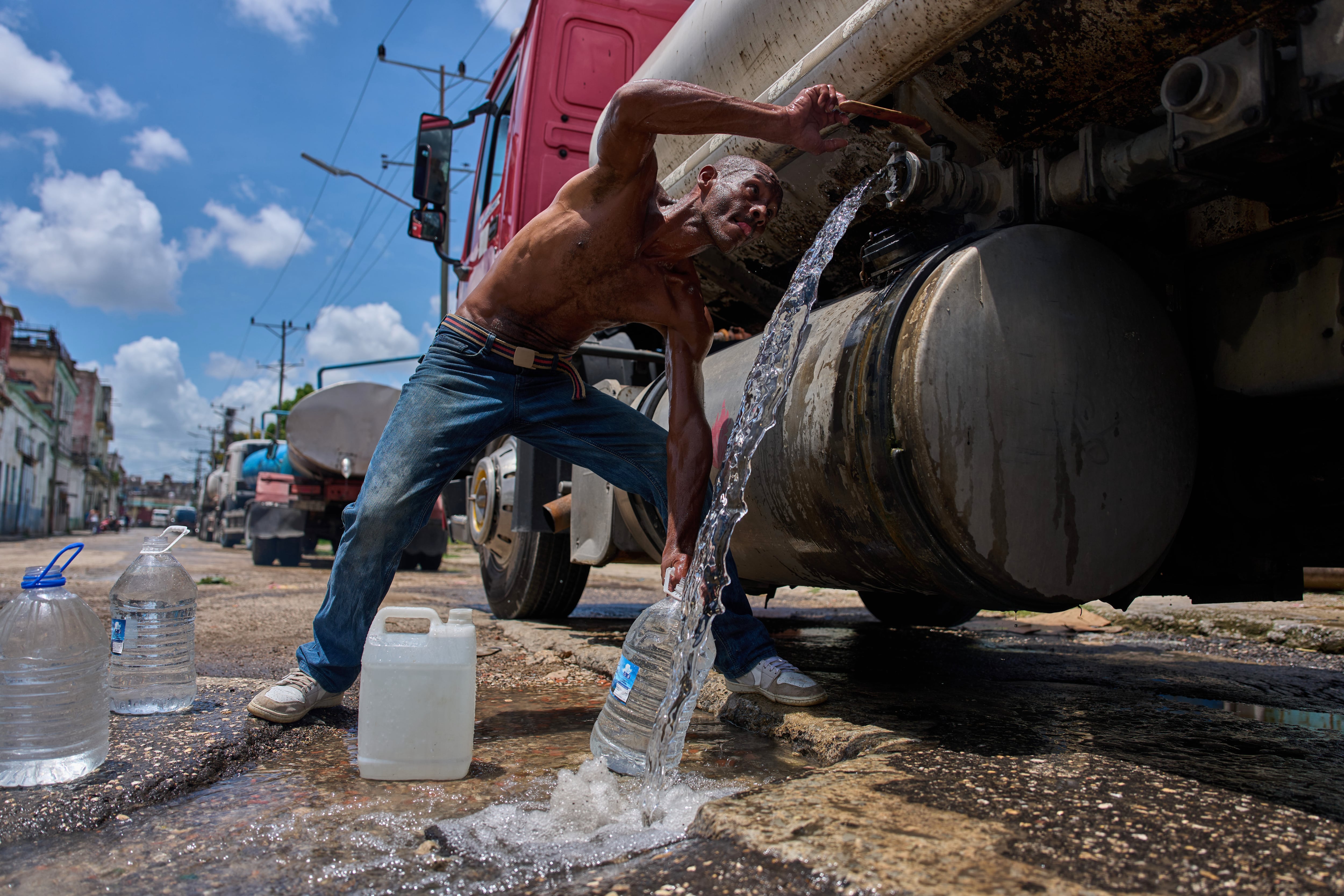 Un hombre llena bidones de agua desde un camión cisterna en La Habana, el jueves 28 de mayo de 2026. (Foto AP/Ramon Espinosa)