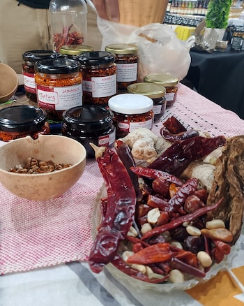 Frascos con salsas de chile, chiles secos, cacahuates, especias, ajos y jengibre en una mesa, y dos cuencos de madera con ingredientes secos