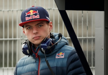 Primer plano de Max Verstappen, un joven de ojos claros, con gorra azul y roja de Red Bull, chaqueta azul acolchada y auriculares al cuello