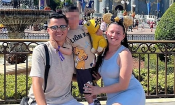 Hombre con gafas de sol, mujer con orejas de Mickey Mouse y niño con rostro pixelado posan sonrientes. Al fondo, fuente y castillo