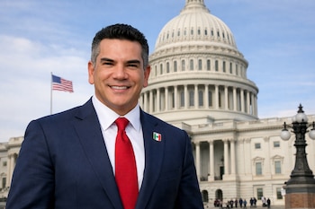 Alejandro "Alito" Moreno sonríe vistiendo un traje azul marino y corbata roja, con un pin de la bandera mexicana, frente al Capitolio de EE. UU. y el cielo azul.