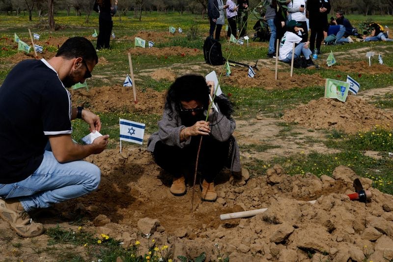 Familiares y cercanos plantan árboles en memoria de las personas que murieron y fueron secuestradas durante el ataque del 7 de octubre en la zona de la fiesta electrónica Nova (REUTERS/Tyrone Siu)
