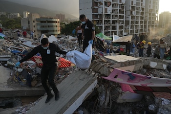Miembros del Cuerpo de Investigaciones Científicas, Penales y Criminalísticas de Venezuela recuperan el cuerpo de una joven a quien la familia encontró entre los escombros de un edificio derrumbado por los dos terremotos, en La Guaira, Venezuela, el miércoles 15 de julio de 2026. (Foto AP/Ariana Cubillos)