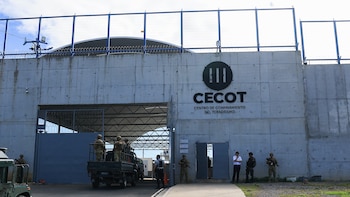 Muro de concreto con el letrero de CECOT, portón de acceso vigilado por efectivos armados y un vehículo militar en la entrada