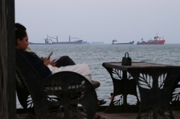 Dos personas revisan sus celulares en un café con vista a buques mercantes en el estrecho de Ormuz, el domingo 12 de julio de 2026, frente a Bandar Abbas, Irán
(Razieh Poudat/ISNA vía AP)