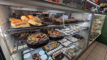 Vitrina iluminada llena de pasteles de chocolate con nueces y cerezas, panes, galletas, pastelitos y otras delicias horneadas