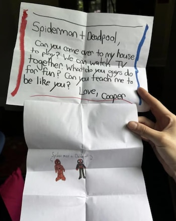Jack Shi, de 64 años, sonríe en la entrada de su casa en Queens, Nueva York, mientras sostiene varias cartas de niños dirigidas a Spider-Man.