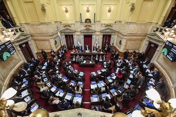 Vista elevada de un recinto legislativo semicircular con personas sentadas en bancas frente a computadoras y pantallas electrónicas