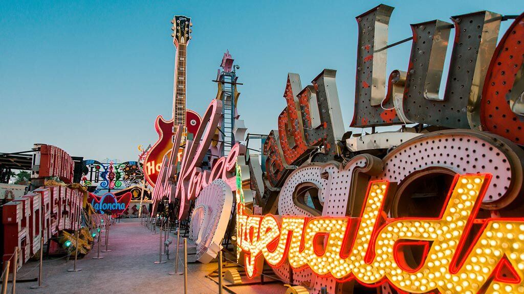 Visitantes recorren el Boneyard del Neon Museum al atardecer, rodeados de letreros que alguna vez iluminaron los casinos y hoteles más famosos de la Strip.