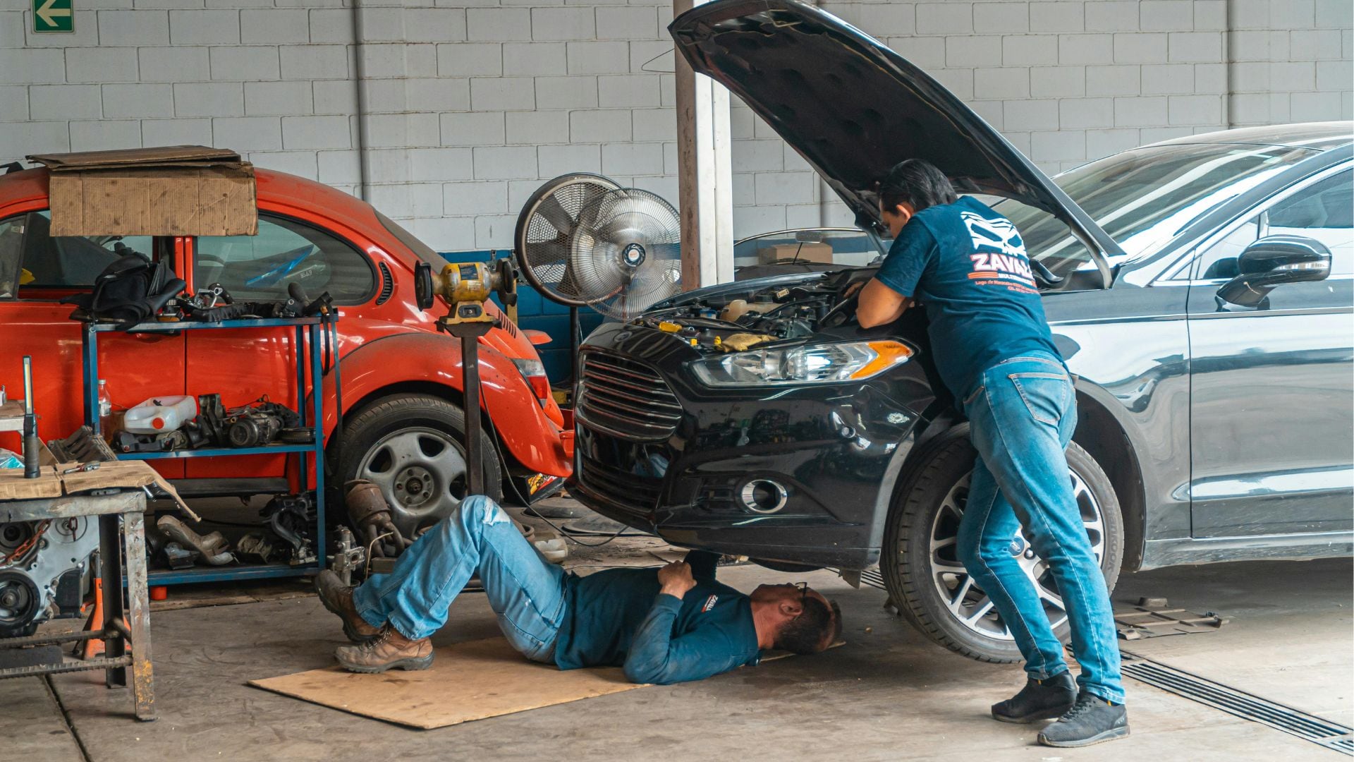 Dos mecánicos arreglan un coche en un taller (Canva)